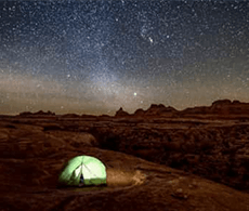 a glowing tent in a desert under starry skies