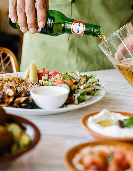A closeup of a drink being poured alongside a plate for delicious food