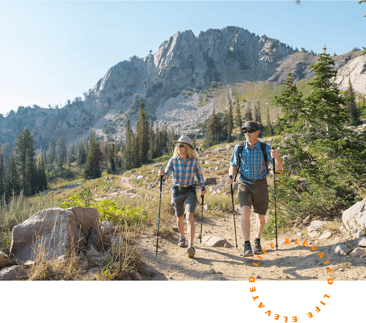 a man and woman hiking through the mountains on a sunny day