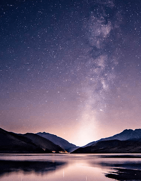 a starry sky over a mountain lake