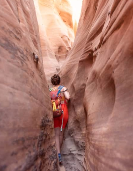 a person walking through a narrow slot in a canyon