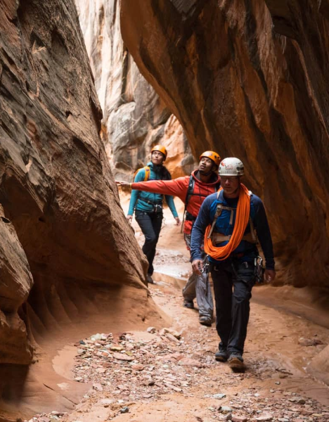 a group of people hiking through a narrow canyon