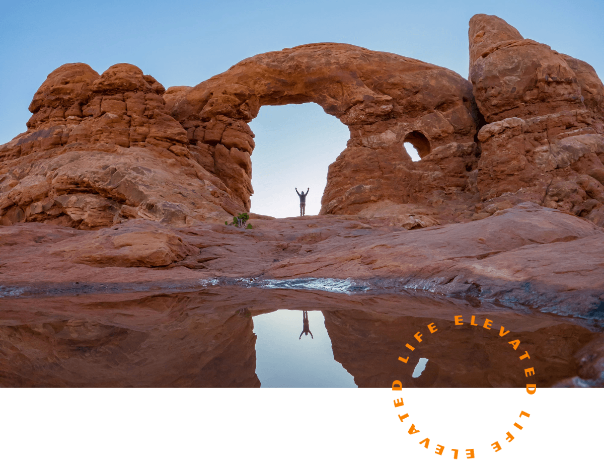 a person standing with their arms raised above their head underneath an arch
