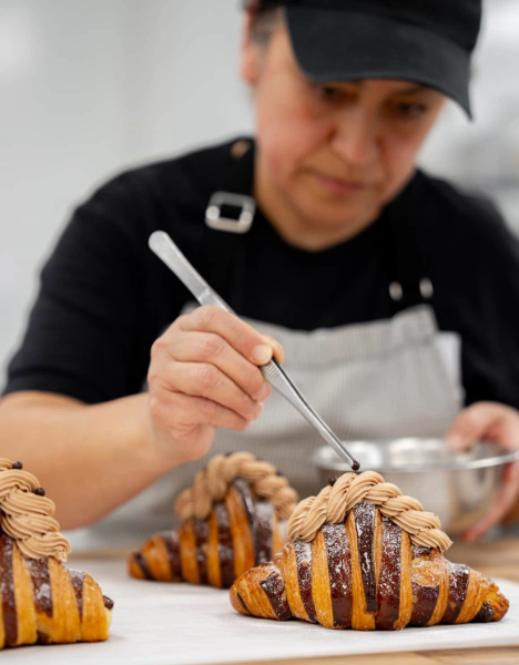 a man in a chef ' s uniform preparing pastries on a table