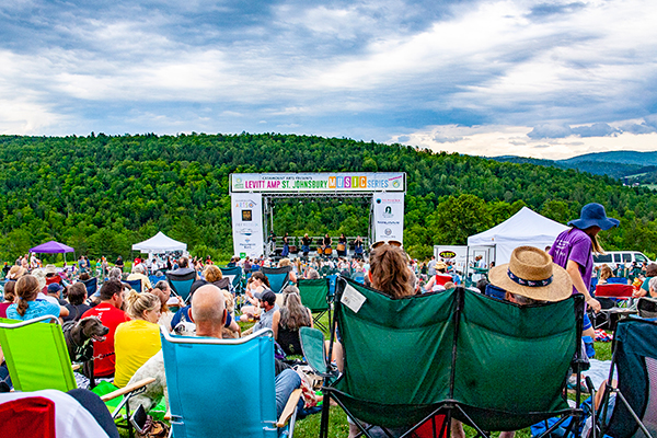 People watch live music on an outdoor stage in the summer.