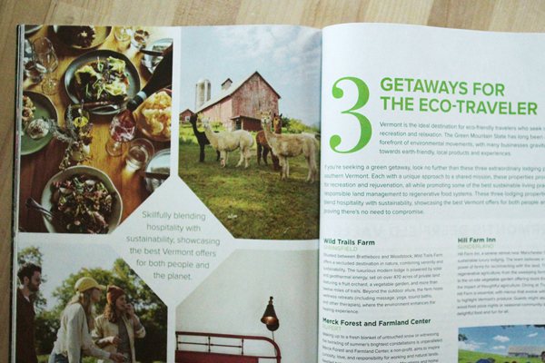 Open on a wood-toned table is a magazine featuring an article titled “3 Green Getaways for the Eco-Traveler,” as well as a variety of advertisements on the left page.