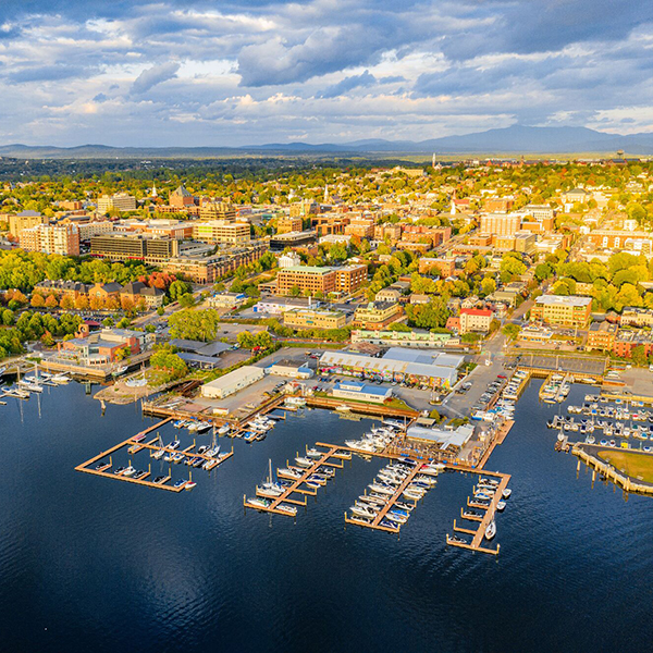 A city seen from overhead, located next to a lake with boats docked. 