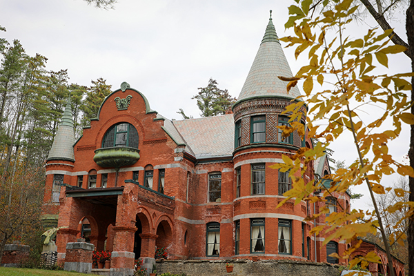 A red brick castle with turrets seen in the late fall, with a few leaves still clinging to tree branches.&nbsp;
