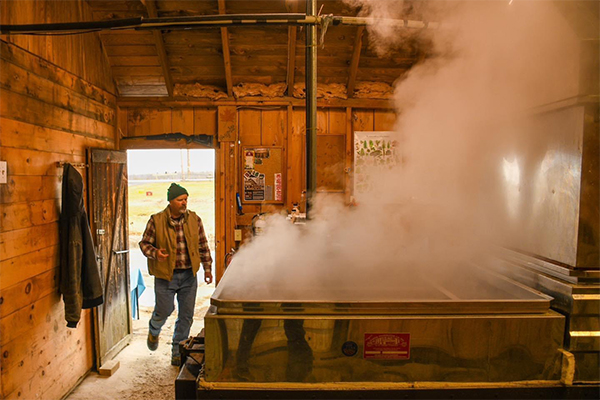 A person enters a wooden room where large metal equipment is producing steam.