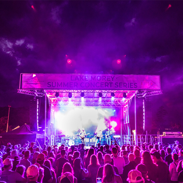 A crowd gathers to enjoy a musical performance with bright lights at night.