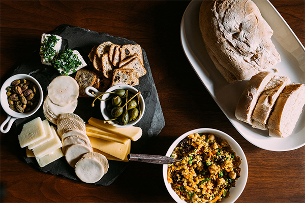 Seen from above, plated food, including cheese and bread, on a table. 