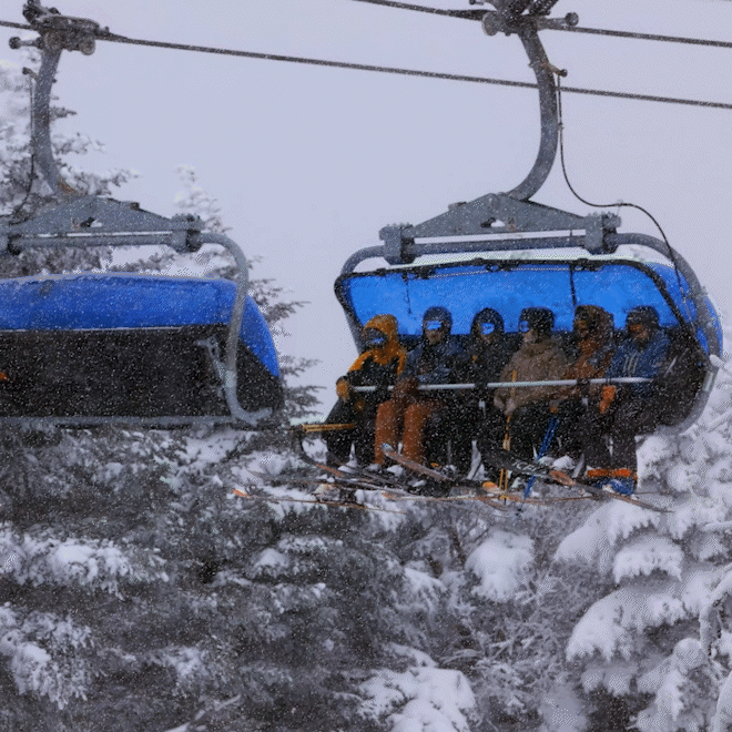 a group of skiers on a ski lift in the snow