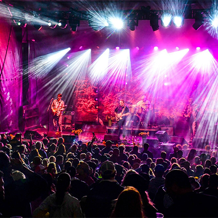 A crowd in an indoor venue at a ski resort watching a live show with bright lights.