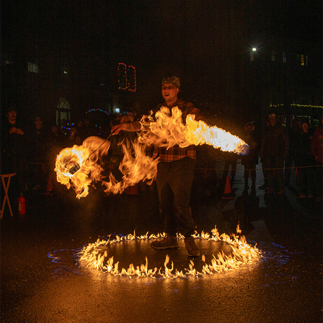 A person performs a dance with fire outside in the winter in the dark. 