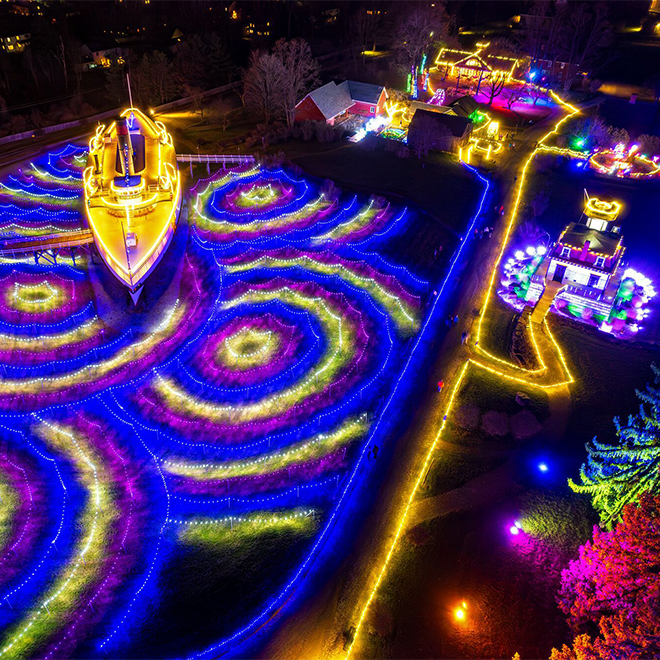 Colorful lights in artistic patterns seen from above at an outdoor evening event, including lights covering a historic steamboat.&nbsp;