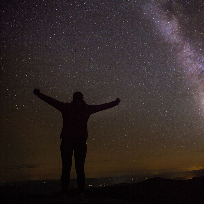 A person seen in silhouette against a night sky with the Milky Way visible.&nbsp;
