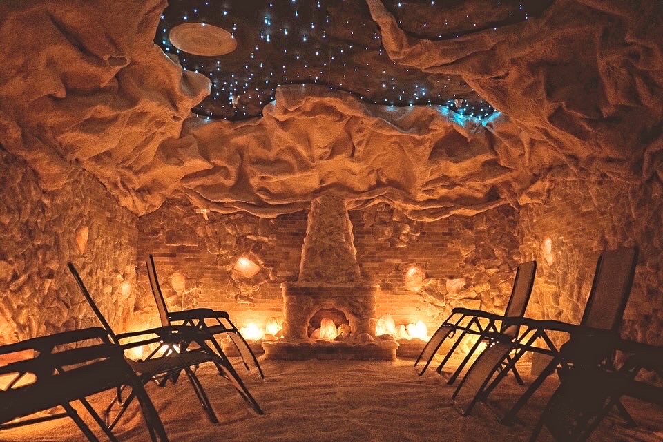 The interior of a warmly lit salt cave with chairs laid around and soft lighting throughout.