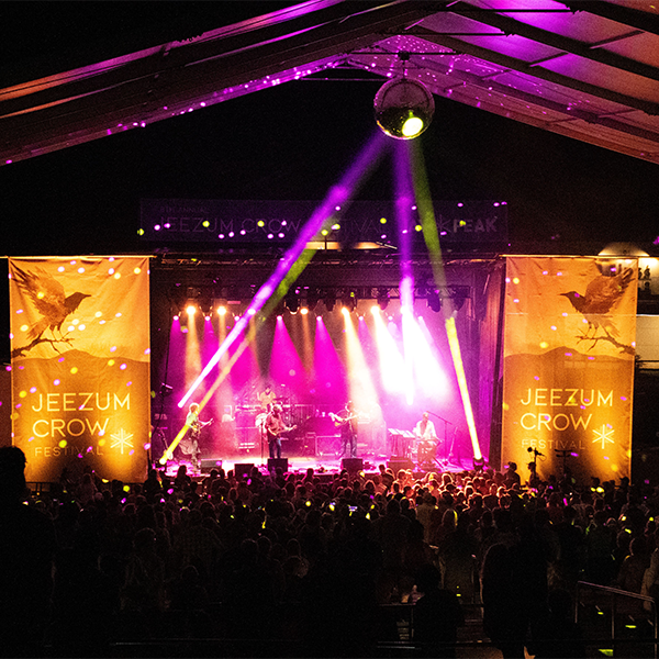Bright, colorful lights illuminate a stage at a music festival at night.&nbsp;