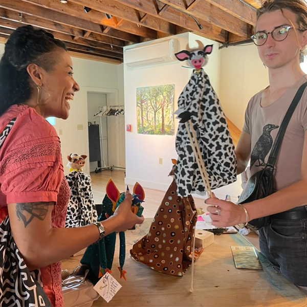 A person shows a puppet to another person, who is smiling.&nbsp;