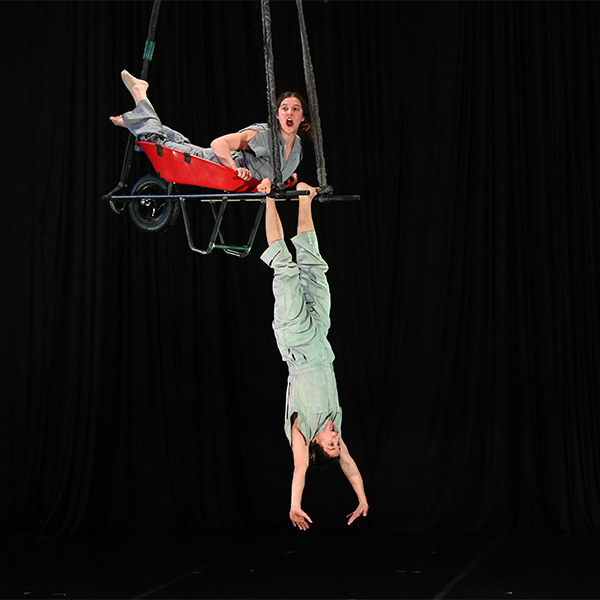 Two people perform a trapeze act at a circus.&nbsp;