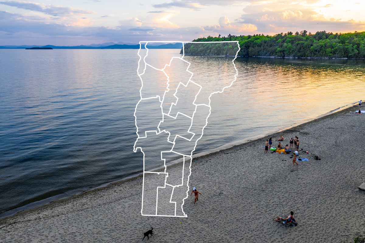 A scenic sunset view of a beach and a large lake, with an illustrated white outline of Vermont showing its regions floating in the center.