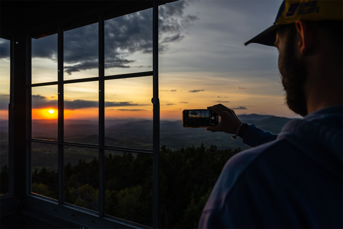 A person standing in a tower taking a picture of a sunset.