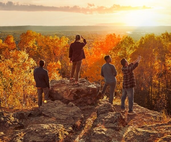 Friends enjoying a beautiful, fall-colored view from a cliff.