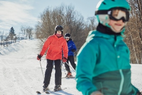 A family skiing down a beginner slope.