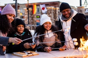 A family roasting marshmallows at an outdoor fire.