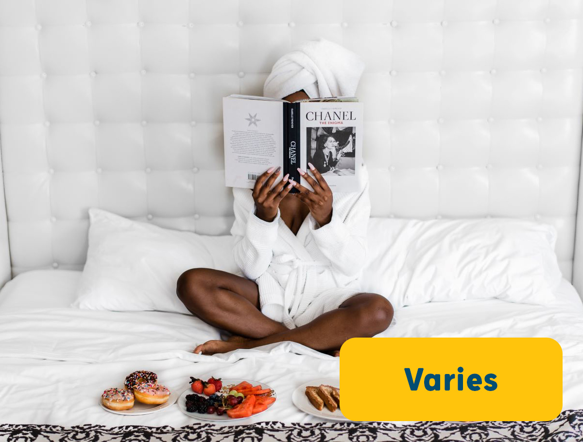 Women sitting on a bed reading a book in a hotel room