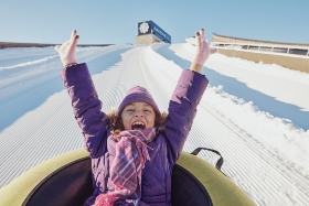 little girl tubbing down snow hill 