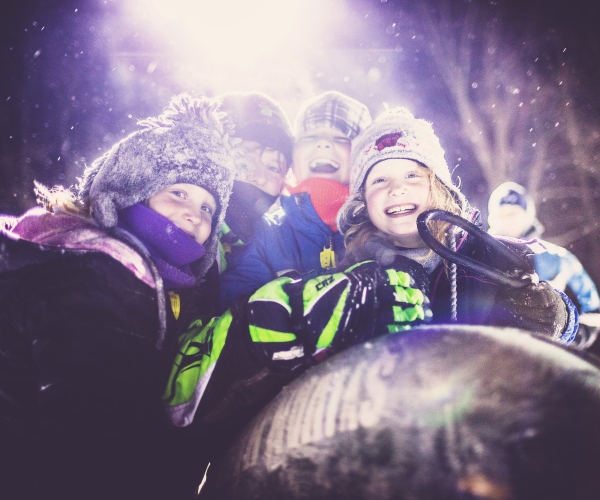 close up of kids smiling while sledding at tubing hill 