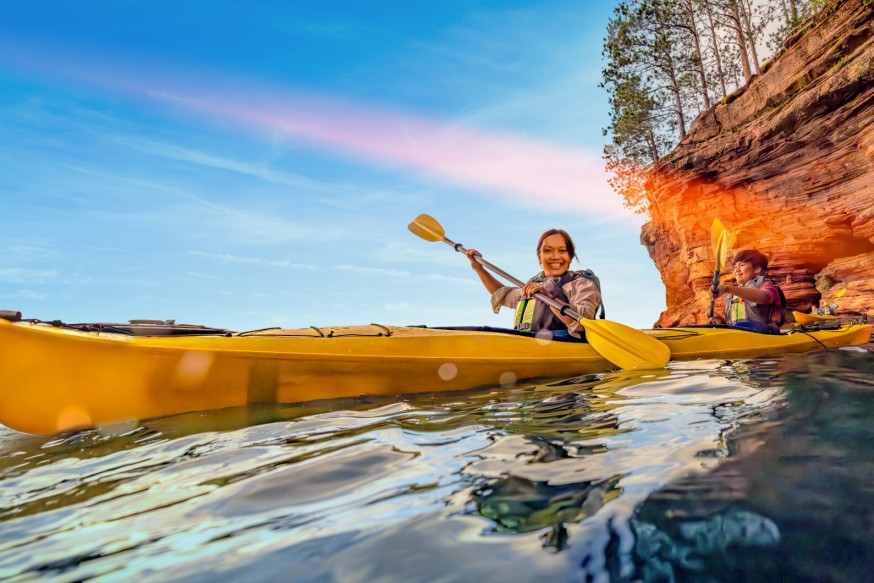 Mother and son kayak along the sea caves of the Apostle Islands during the sunset.
