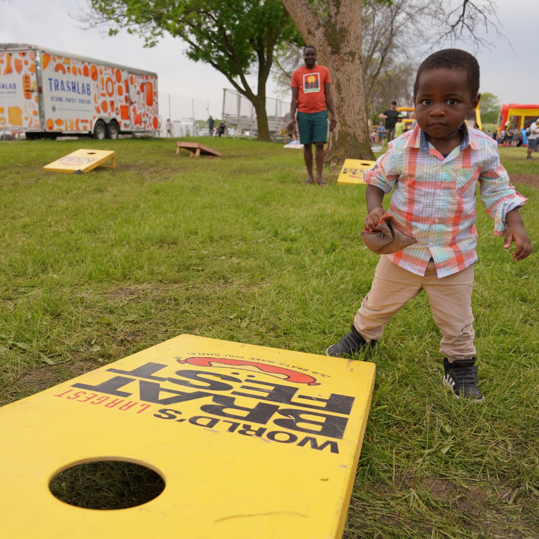 little boy playing bean bag toss with dad at brat fest