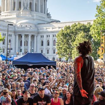 musician on stage in front of a crowd in the Madison capital square 