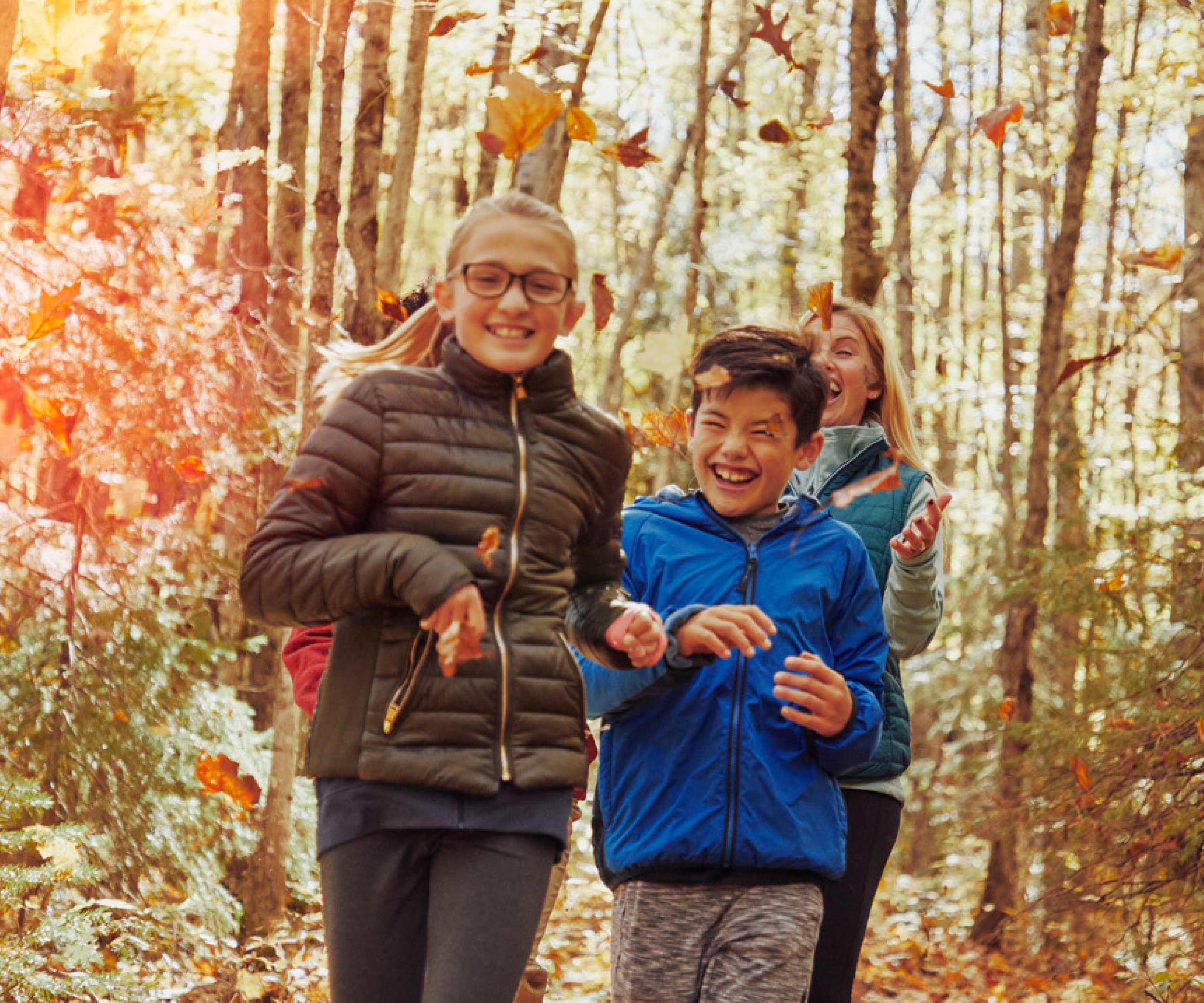 kids laughing and running through a wooded trail during fall 