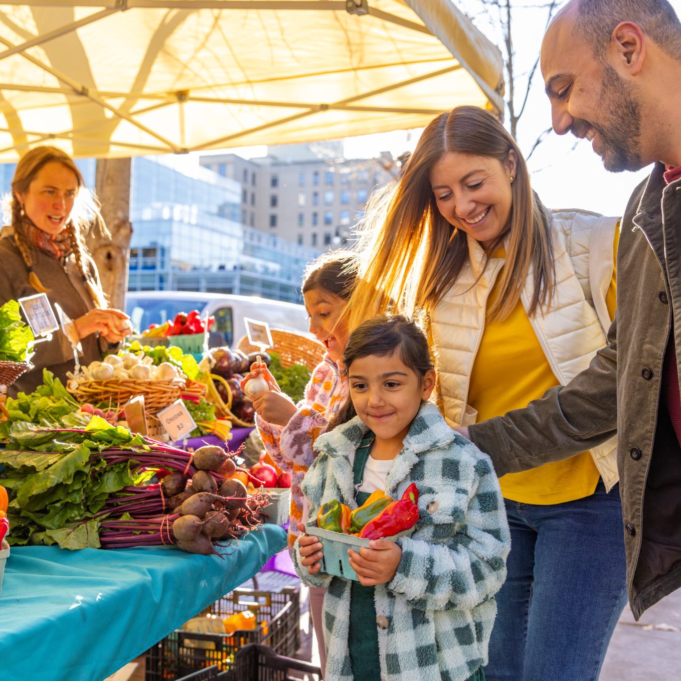 family looking at garden vegetables from vendor at dane county farmers market 