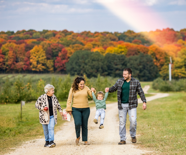 family walking along a path with beautiful fall color behind them 