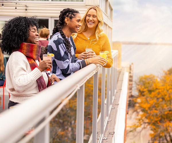 girl friends standing on the balcony of an outdoor bar overlooking scenic fall color