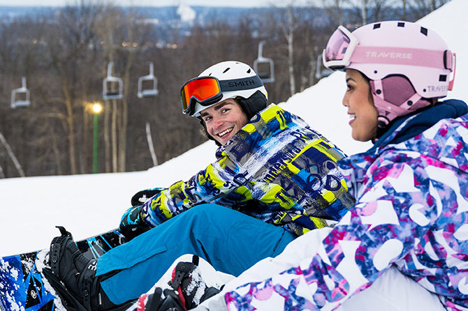 friends sitting in the snow while snowboarding
