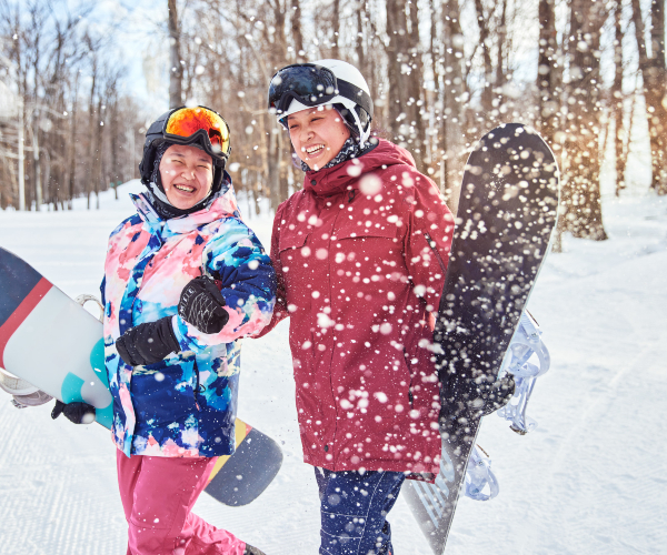 friends walking through the snow carrying snowboards