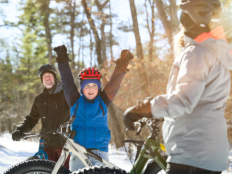 little boy raising his arms in excitement while stopping with family along fat tire bikie trail