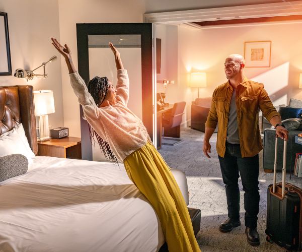 woman smiling and falling onto a hotel bed