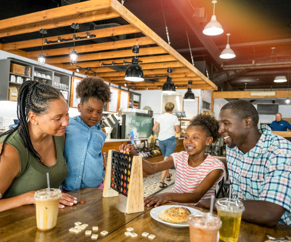 little girl holding a slice of pizza while smiling at her mother 