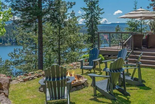 A mountain-side scene with chairs around an open fire.  