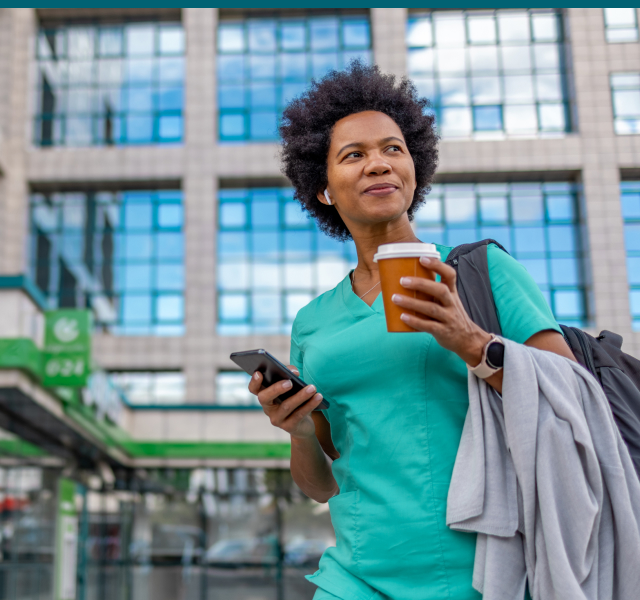 Woman Standing in Front of an Office Building holding a coffee and phone 