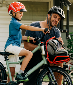 Father helps his young son get ready to ride his woom NOW to school