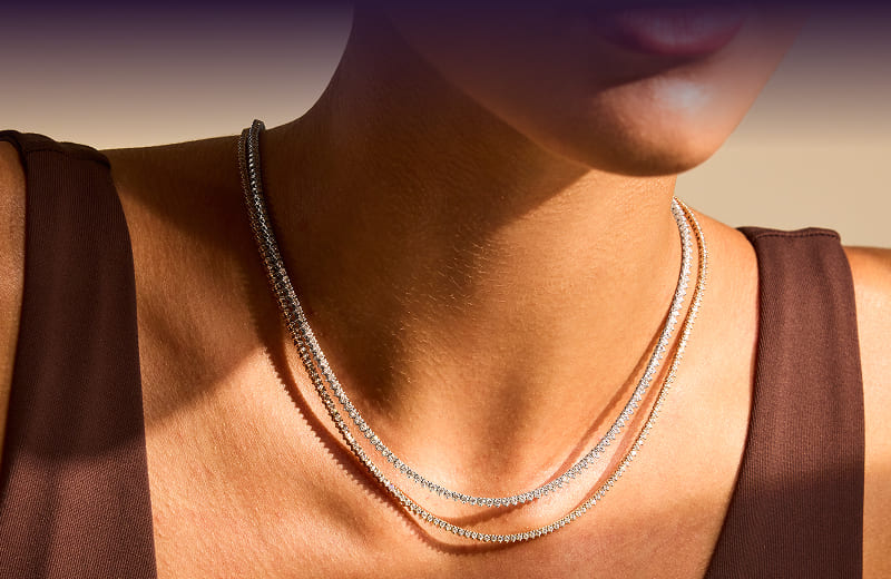 A model wearing three gold diamond necklaces. Stellar Allure. Wrap something stellar. Click here to shop now
