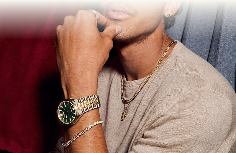 A model wearing gold jewelry and a two-toned watch. 
