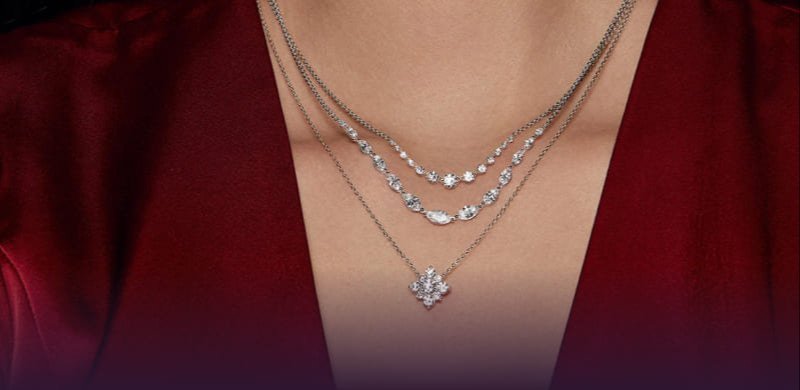 Close-up of model's neck with three diamond necklaces. 